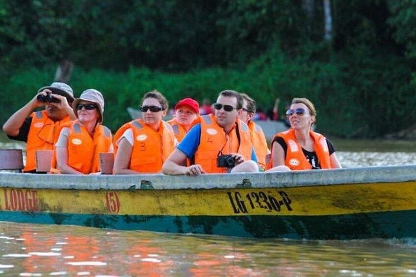 A group of people in a boat wearing orange life jackets. 5