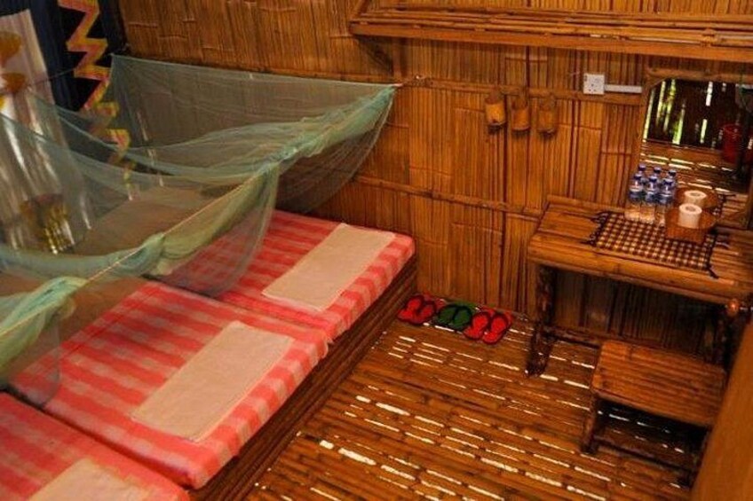 A bamboo room with a bed, a small table, and a chair. 3