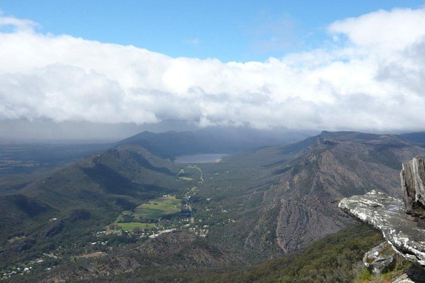 A mountainous landscape with a valley, a winding road, and a rocky outcrop. 1