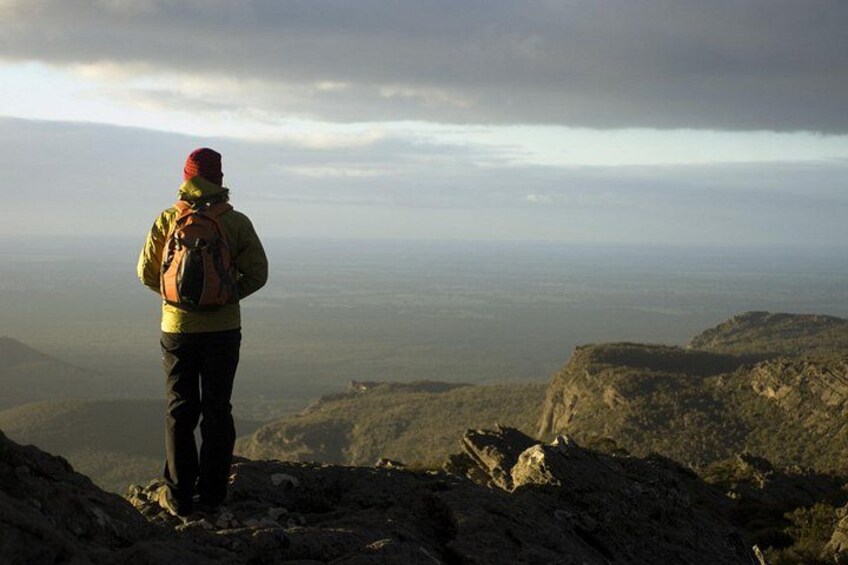 A person standing on a rocky outcrop overlooking a vast landscape. 5