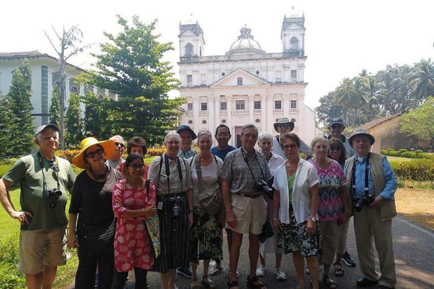 Un grupo de personas frente a un edificio histórico grande con cúpulas y un campanario. 2