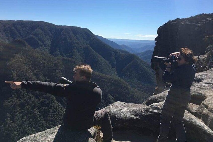 Two people on a rocky outcrop overlooking a valley. 3