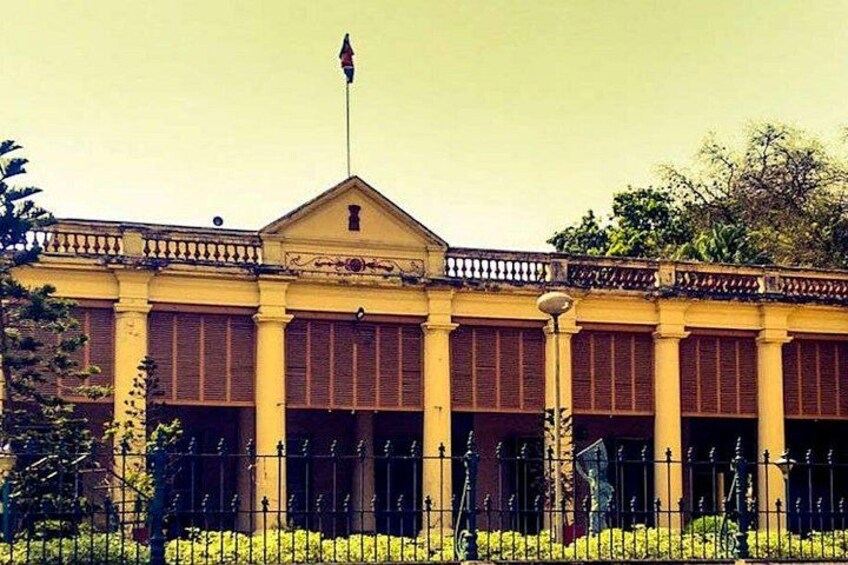 A building with a yellow facade, columns, and a flagpole. 5