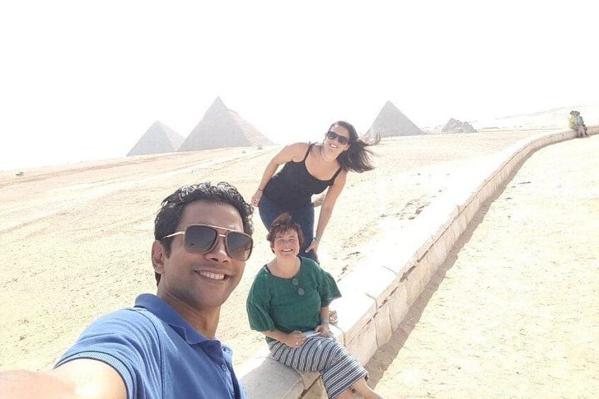 A person taking a selfie with pyramids in the background. 4