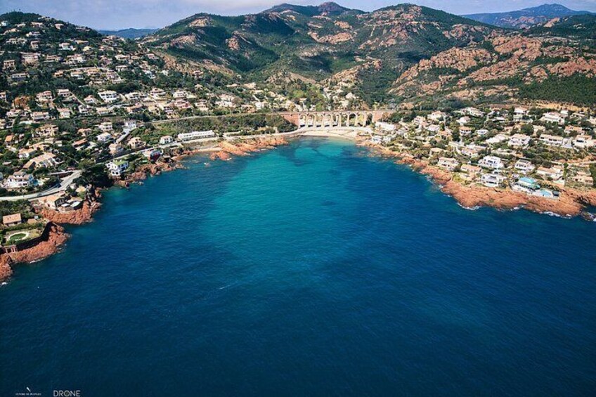 A coastal town with houses along the shoreline, a bridge, and mountains in the background. 2