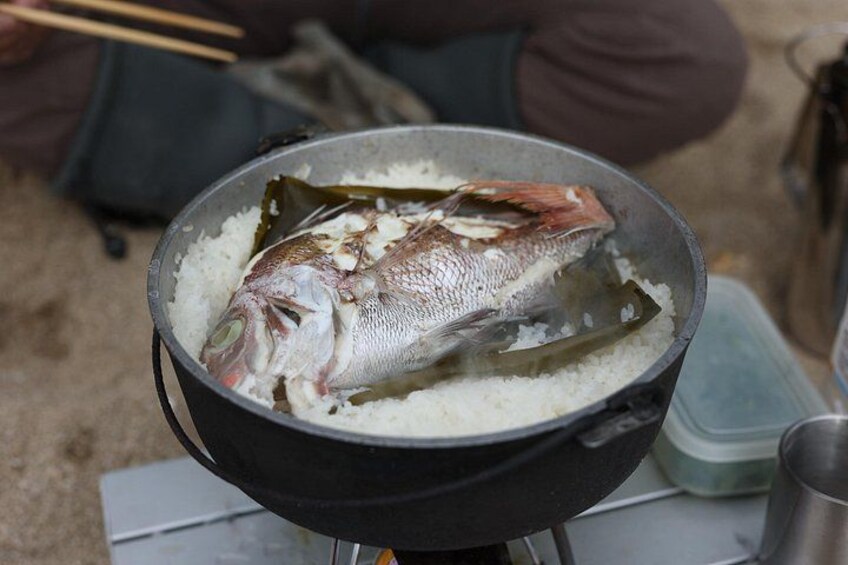 A fish being cooked in a pan with rice. 3