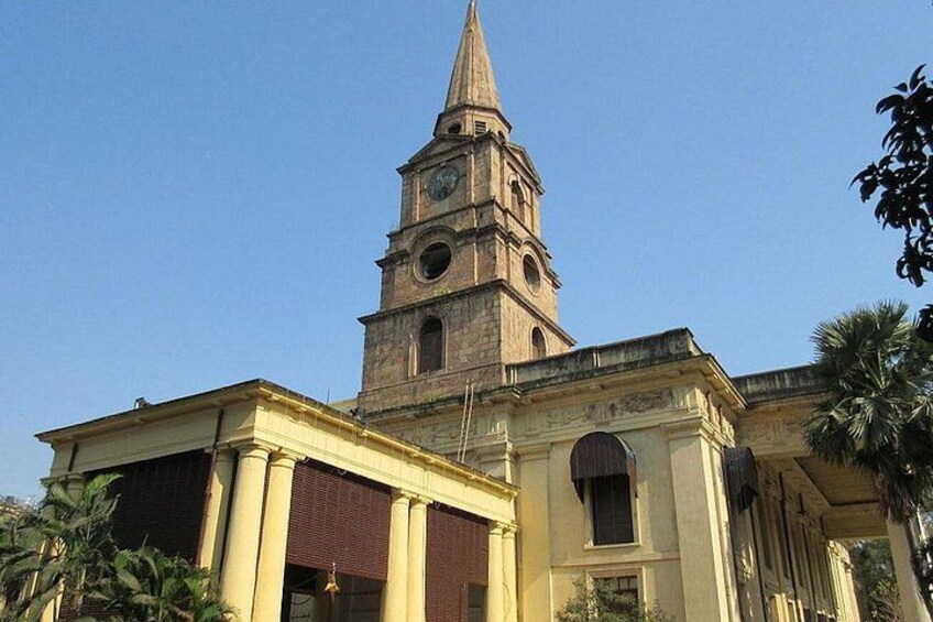 Un edificio histórico con una torre de reloj, un gran arco de entrada y una torre de campanas. 4