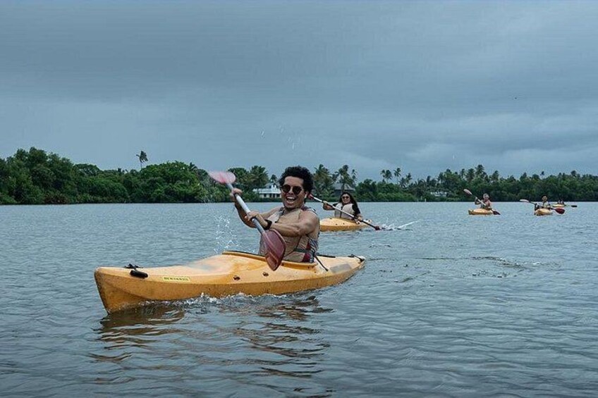 People kayaking on a calm body of water with a forested shoreline in the background. 2