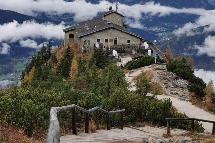 Eine Berglodge mit einer Holztreppe, umgeben von Bäumen und Wolken. 1