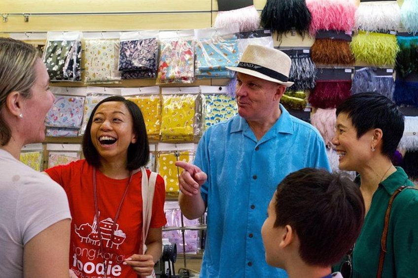 A group of people in a fabric store with various colorful fabrics on display. 3