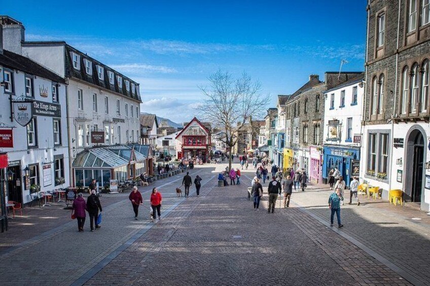A cobblestone street lined with historic buildings, a pub named 'The King Arms,' and a clear blue sky. 4