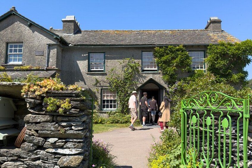 A stone house with a green gate, a stone wall, and a pathway. 1