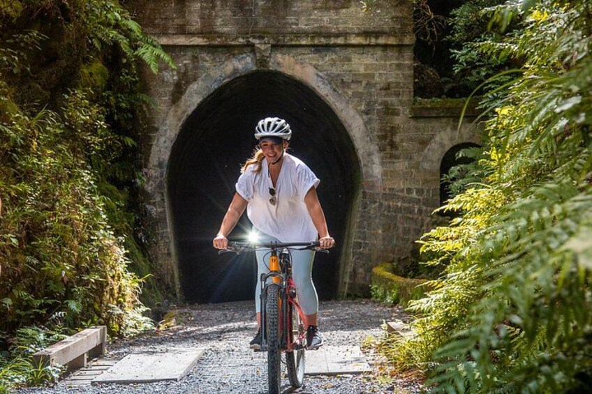 Une personne à vélo traverse un tunnel bordé de verdure. 2