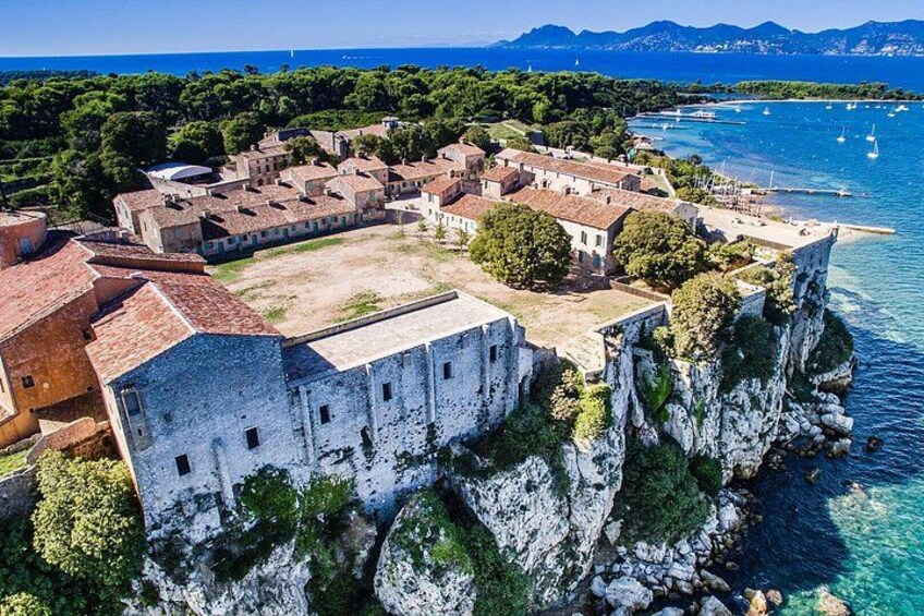 Un pueblo costero con edificios históricos, una estructura fortificada y aguas azul turquesa. 3