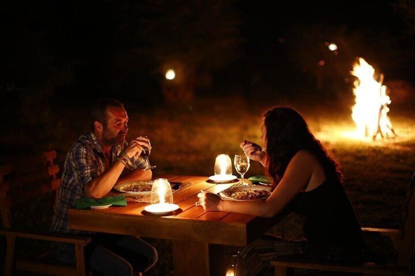 Two people dining at a table with candles and a fire in the background. 3