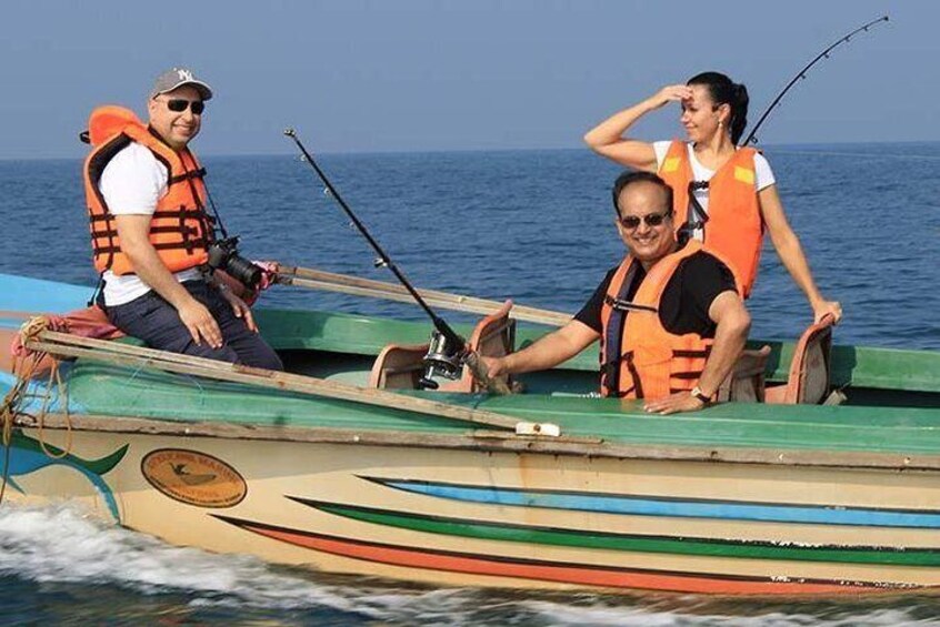 Three people on a small boat with fishing rods, wearing life jackets. 5