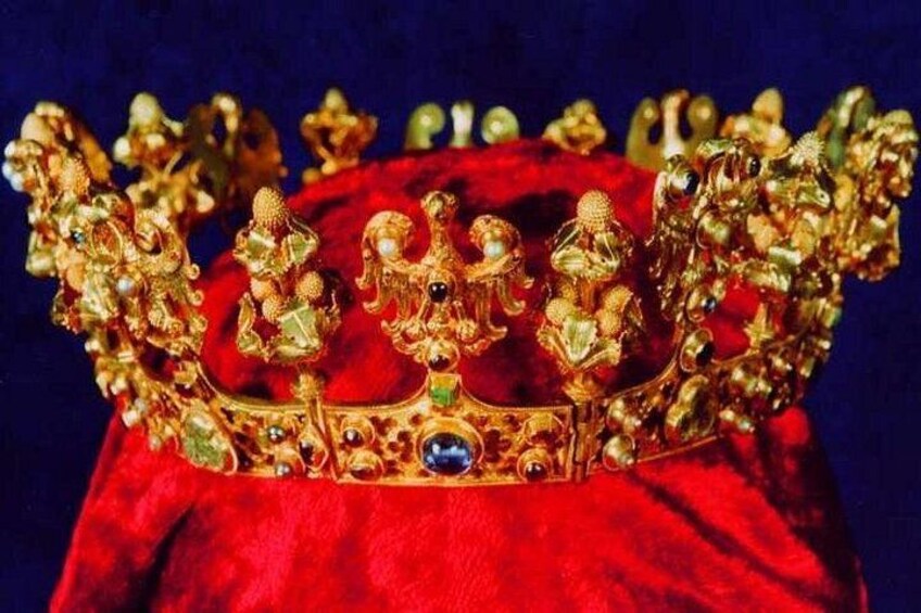 A gold crown with intricate designs and a central gemstone. 1