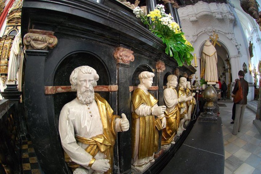 A church interior with statues of religious figures, ornate decorations, and a checkered floor pattern. 4
