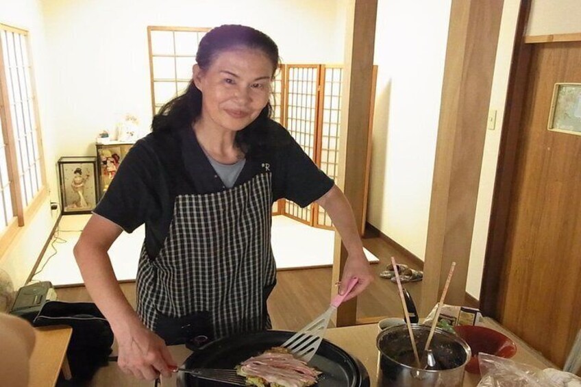 A person cooking in a kitchen with a frying pan on the stove. 5