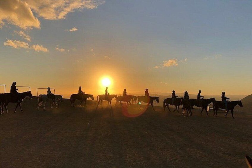 Un grupo de personas montando a caballo en un paisaje desértico durante el atardecer. 2