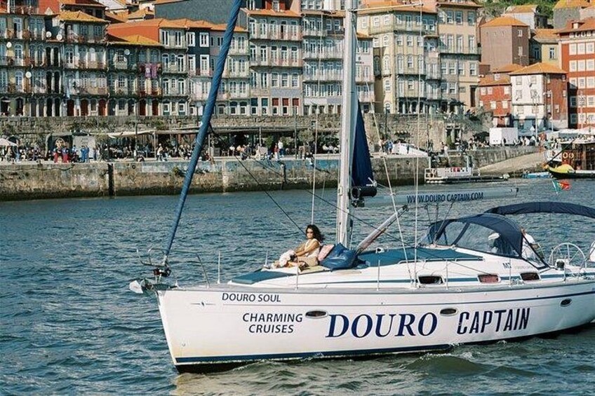 A sailboat named 'Douro Captain' docked near a waterfront with buildings in the background. 4
