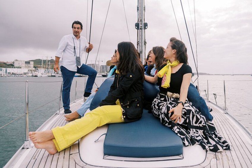 A group of people on a sailboat with a city marina in the background. 3
