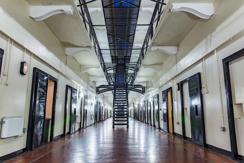 A long, well-lit hallway with a central staircase, flanked by doors and light fixtures. 4