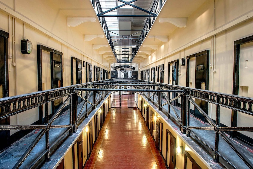A long corridor with a metal railing, doors, and a tiled floor. 3
