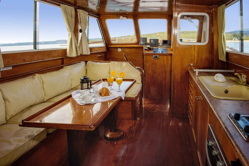 A cozy interior with a wooden dining table set for breakfast, a cushioned bench, and a small kitchenette. 4