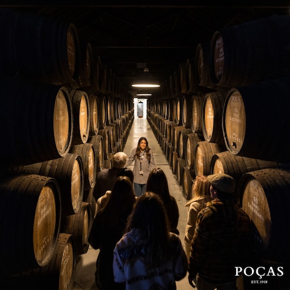 A person walking down a corridor lined with wooden barrels. 1