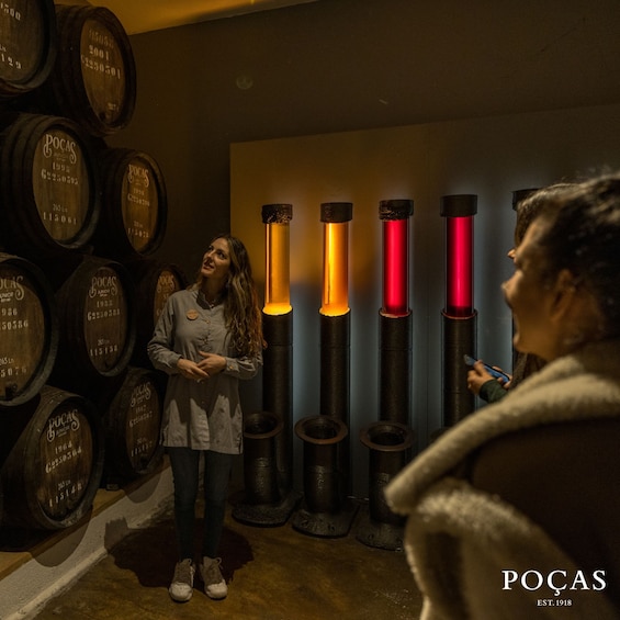 A person standing in a cellar with wooden barrels and illuminated columns. 4