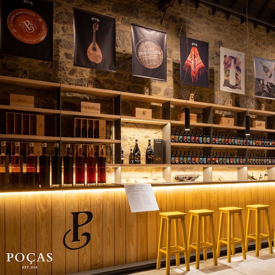A bar with wooden shelves and stools, featuring a stone wall and various wine bottles. 5