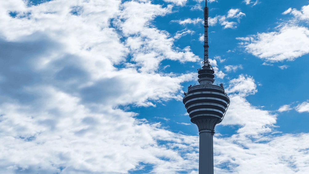 A tower with a spiral design against a blue sky with clouds. 1