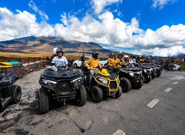 A group of people on ATVs in a parking area with a mountainous landscape in the background. 2