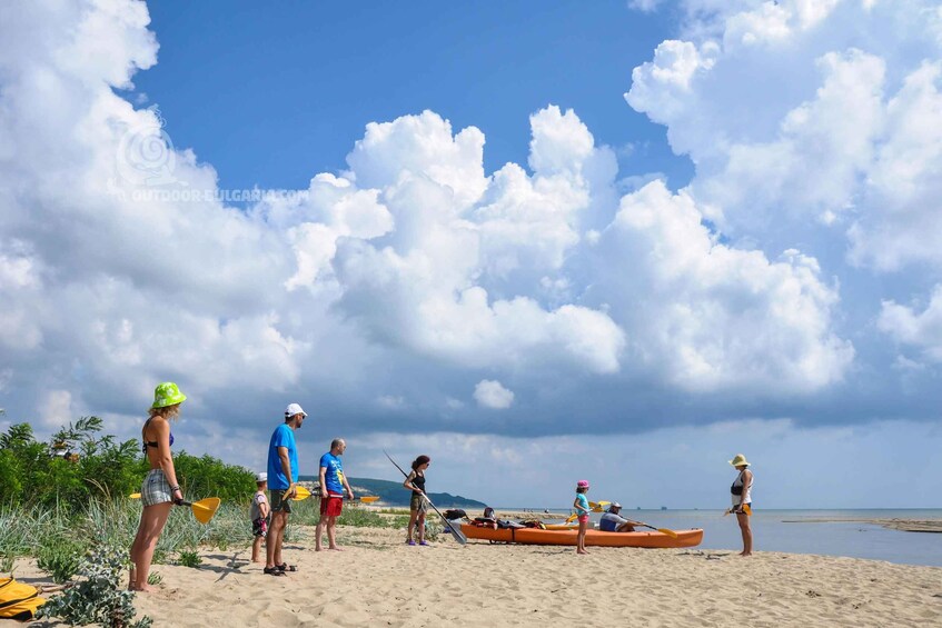 Un grupo de personas en una playa con kayaks y tablas de remo, preparándose para actividades acuáticas. 2