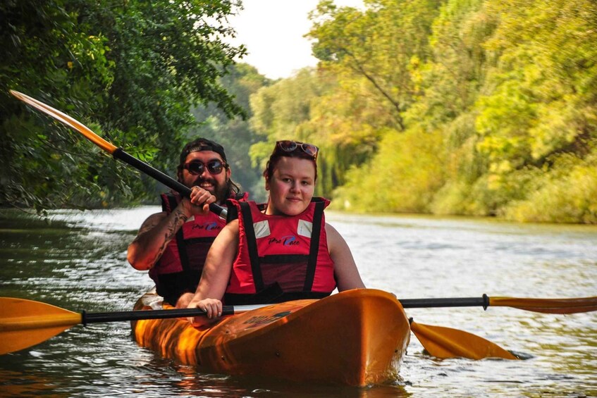 Dos personas remando en kayak por un río rodeado de abundante vegetación. 4