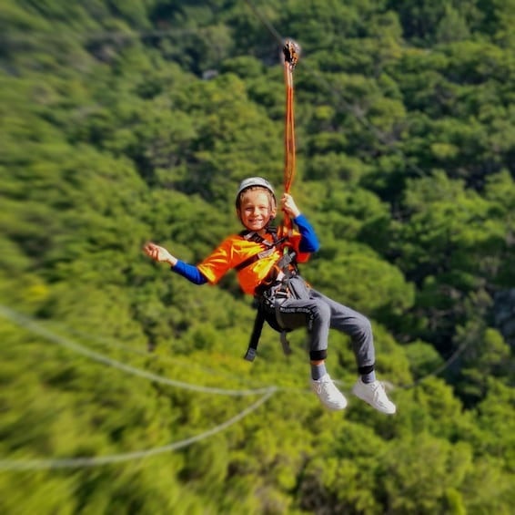 A person bungee jumping with a harness and safety gear, suspended in mid-air with a forested landscape in the background. 2