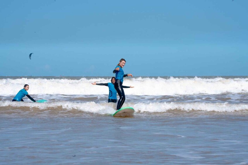 Two people surfing on a wave with a clear sky and a distant kite in the background. 4