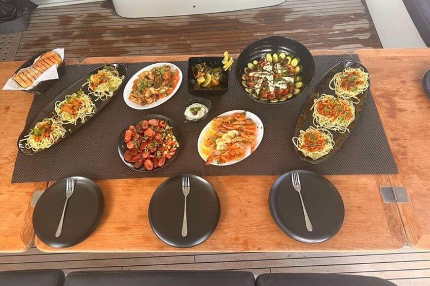 A wooden table with various dishes of pasta and salads, arranged on a dark placemat. 4