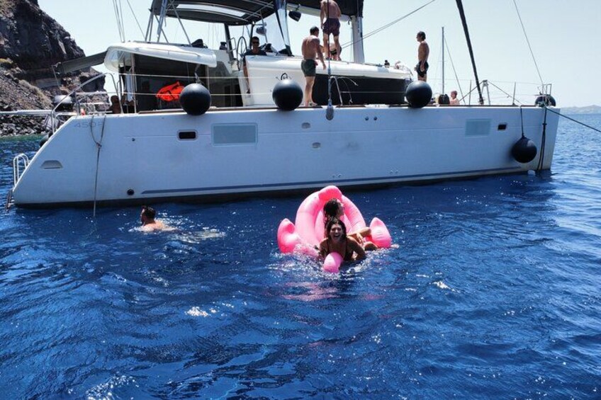 A white yacht with people on deck and a pink inflatable in the water. 5