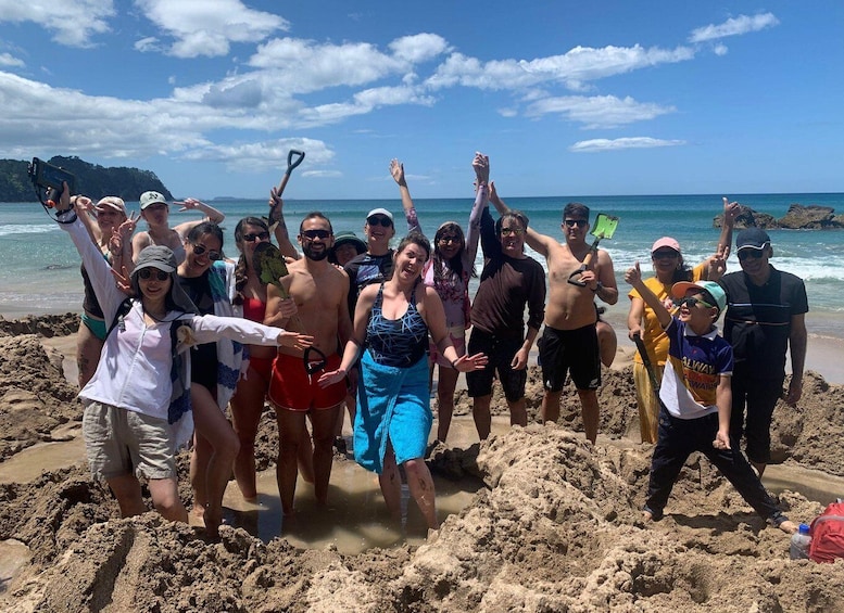 A group of people on a sandy beach with the ocean and a clear sky in the background. 5