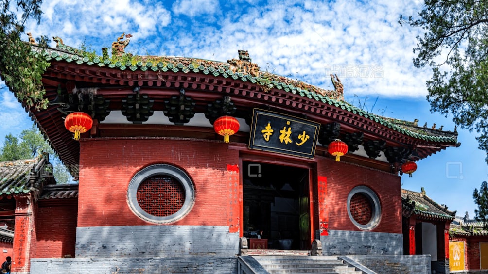 A traditional Chinese building with red walls, green tiled roof, and circular windows. 4