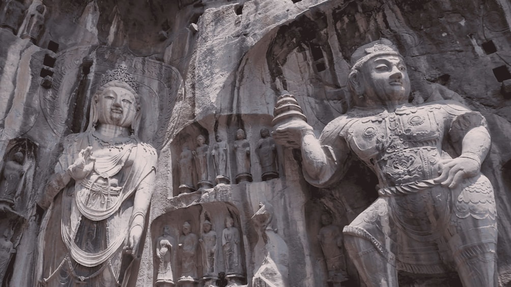 A detailed stone carving of a figure in armor and another in a robe, with smaller figures in the background. 3