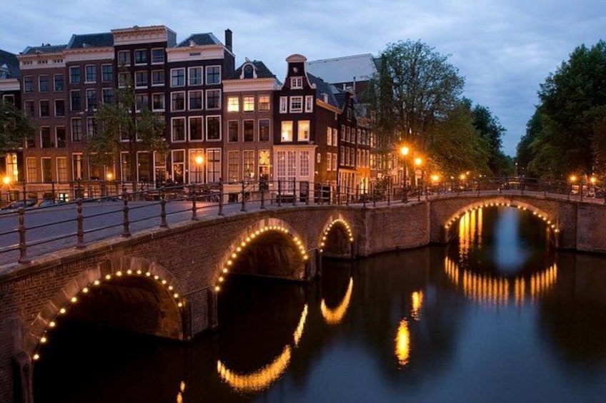 Ein Kanal mit einer Brücke, Gebäuden und Lichtern, die sich im Wasser spiegeln. 4