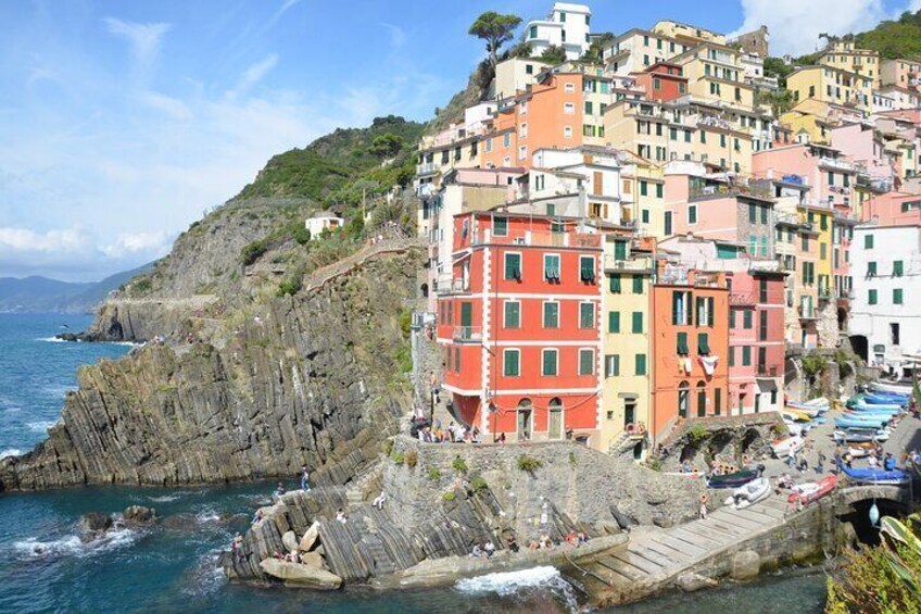 Colorful buildings along a rocky coastline with a pier and boats. 1