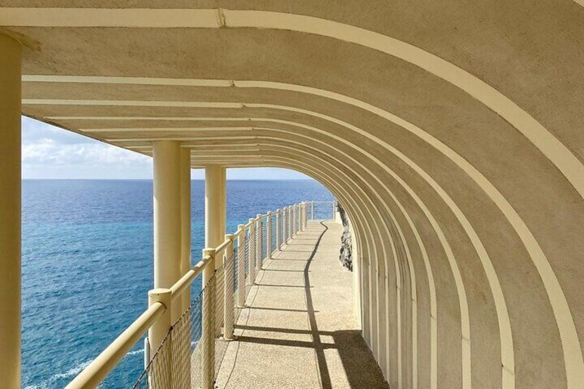 A curved walkway with a railing overlooking the ocean. 3