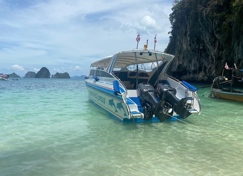 A boat named 'Aloha Seacour' anchored near a rocky coastline with clear turquoise water. 3