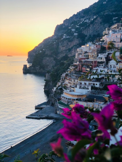 A coastal village with colorful buildings perched on a cliff overlooking the sea at sunset. 1