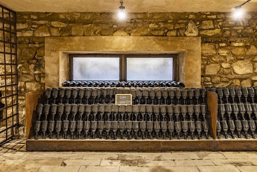 A wine cellar with rows of wine bottles and a window above. 2