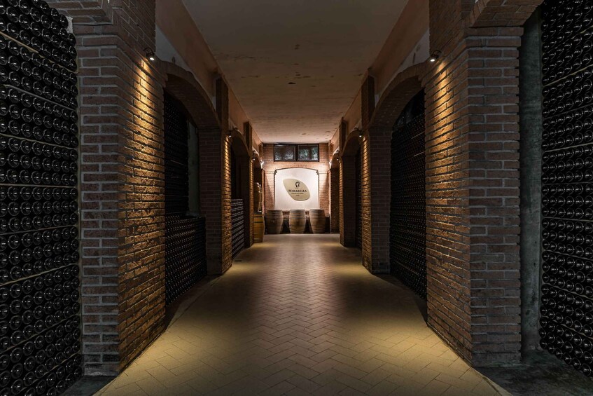 A wine cellar with brick walls and rows of wine bottles. 1